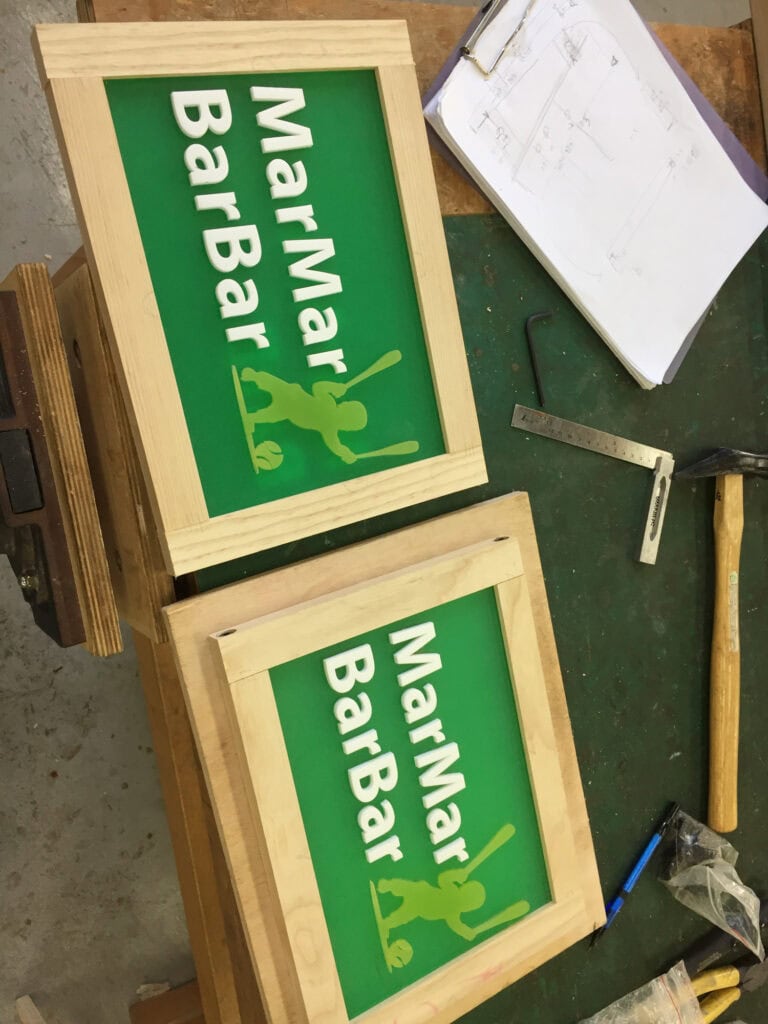 兩面新做的綠底白字 MarMar BarBar 招牌，外圈包著原木框