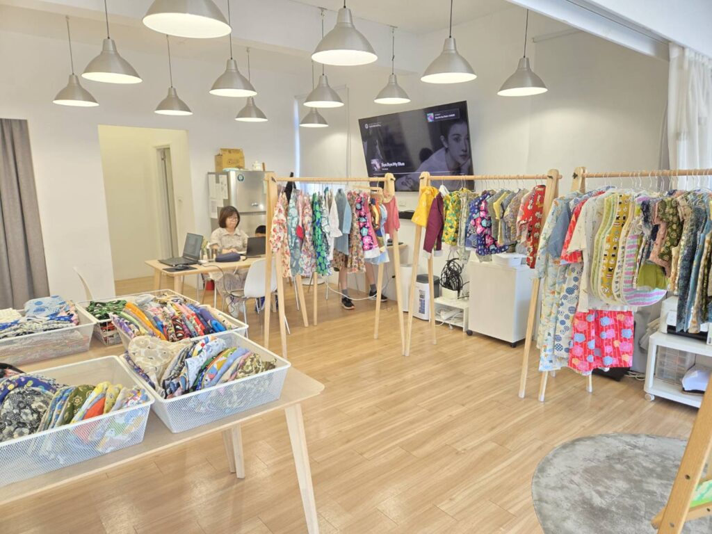 Marmarbarbar 快閃店內景：兩組小白鷺衣架掛滿童裝，桌上的籃子裡疊著布料